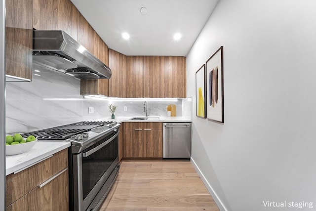 kitchen featuring modern cabinets, appliances with stainless steel finishes, under cabinet range hood, and a sink