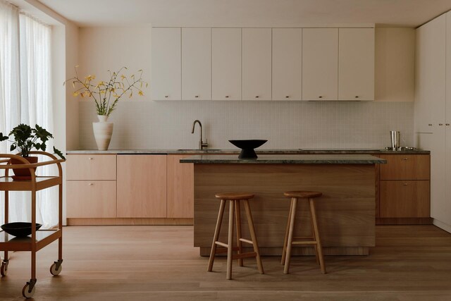 bar featuring backsplash, a sink, and light wood-style flooring