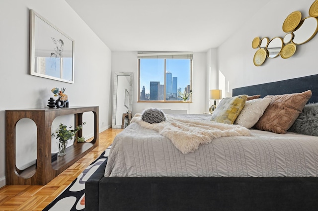 bedroom featuring parquet flooring, a view of city, and baseboards