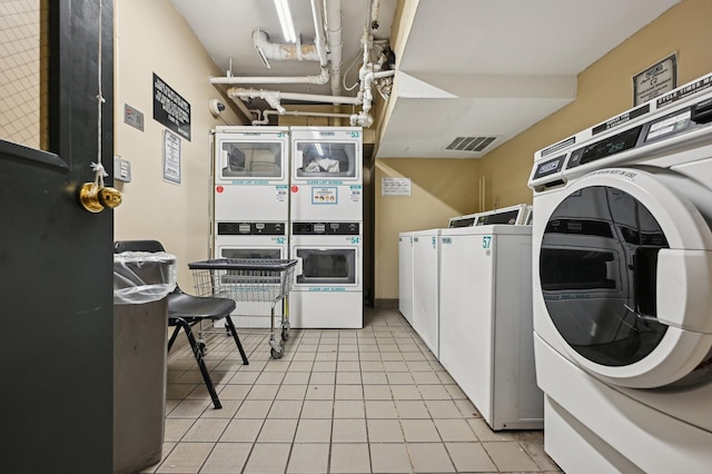 shared laundry area with stacked washer / drying machine, visible vents, washing machine and clothes dryer, and light tile patterned flooring