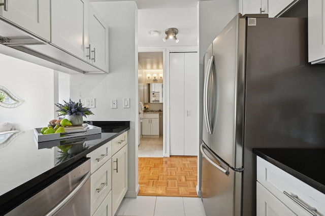 kitchen featuring dark countertops, appliances with stainless steel finishes, and white cabinetry