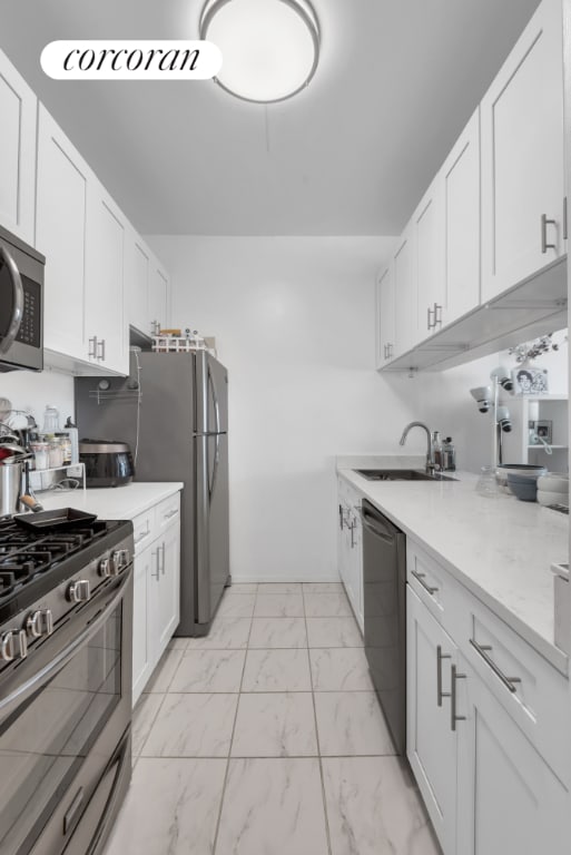 kitchen featuring light stone counters, sink, white cabinets, and appliances with stainless steel finishes