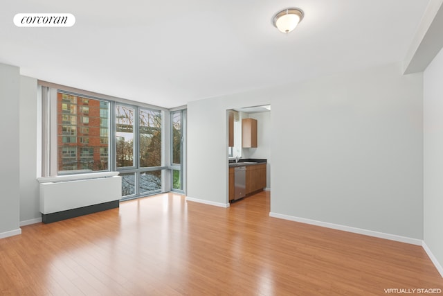 unfurnished living room featuring a wall of windows, visible vents, baseboards, and light wood-style floors