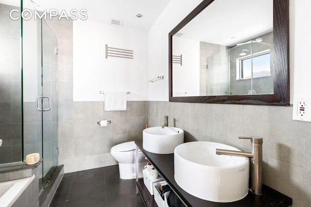 full bathroom featuring toilet, tile walls, vanity, plus walk in shower, and tile patterned flooring