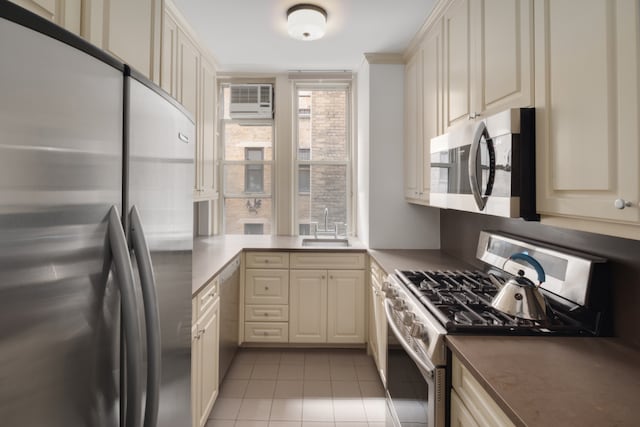 kitchen featuring stainless steel appliances, an AC wall unit, a sink, and cream cabinetry