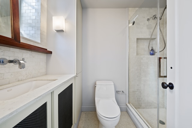 bathroom featuring toilet, decorative backsplash, a stall shower, vanity, and baseboards