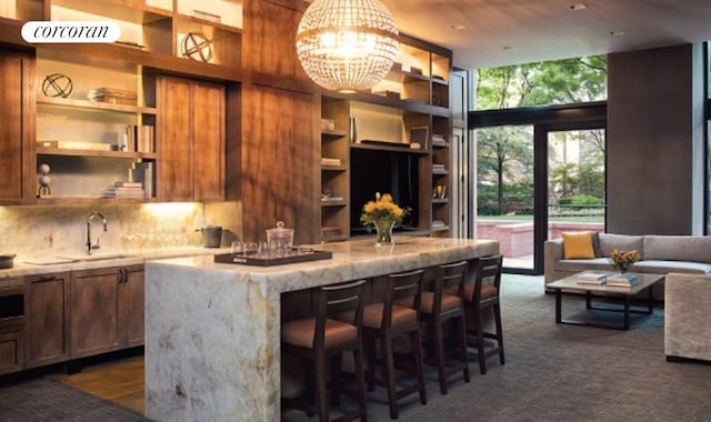 bar featuring an inviting chandelier, sink, a wall of windows, light stone countertops, and decorative backsplash