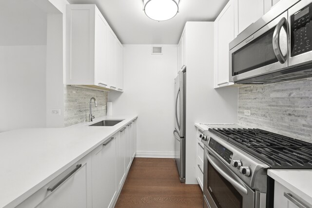 kitchen featuring tasteful backsplash, stainless steel appliances, white cabinets, dark hardwood / wood-style flooring, and sink