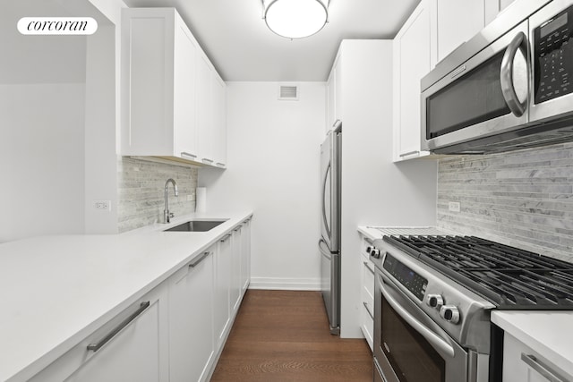 kitchen with white cabinetry, dark hardwood / wood-style flooring, sink, appliances with stainless steel finishes, and decorative backsplash