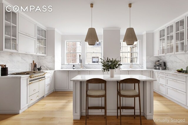 447 E 57th St Unit 14, New York City, NY 10022 - kitchen with cooktop, a center island, backsplash, light wood-style floors, and crown molding