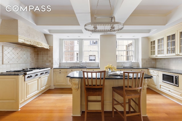 447 E 57th St Unit 14, New York City, NY 10022 - kitchen featuring stainless steel appliances, backsplash, light wood-style floors, glass insert cabinets, and a kitchen island