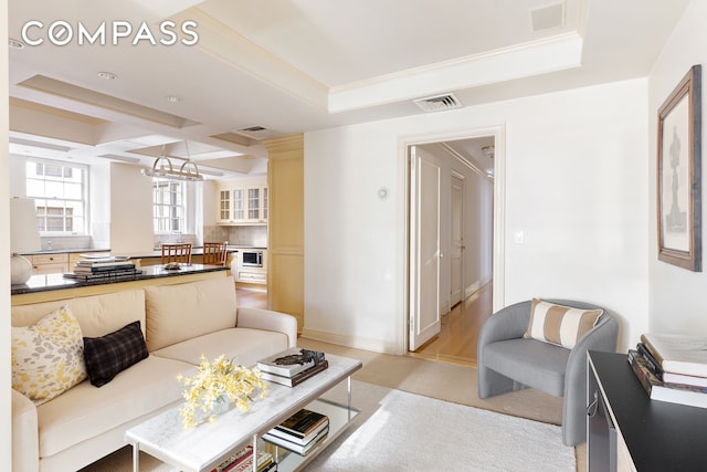 living room featuring a raised ceiling, visible vents, and ornamental molding