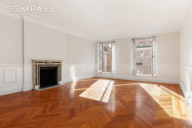 unfurnished living room featuring a fireplace with flush hearth, wainscoting, and ornamental molding