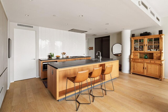 kitchen featuring a kitchen island with sink, sink, oven, and stainless steel gas stovetop