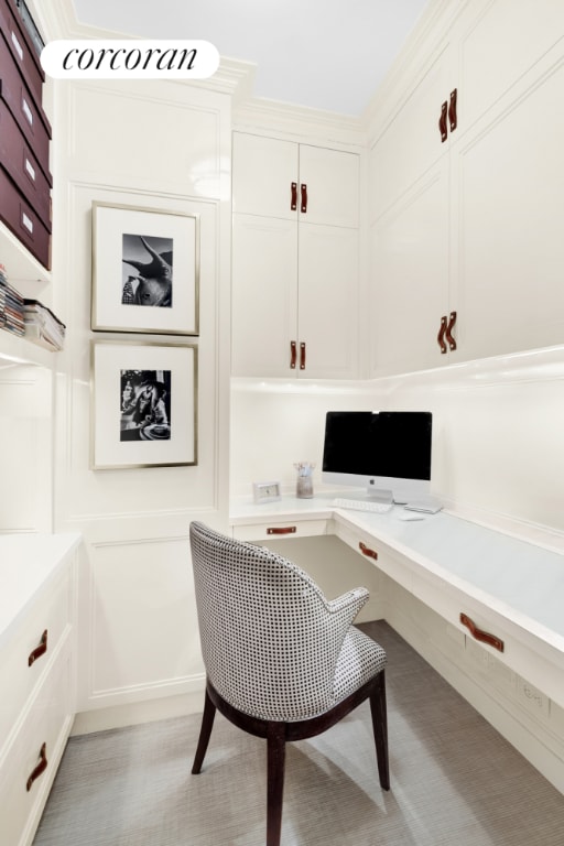 office area with ornamental molding, a decorative wall, and built in desk