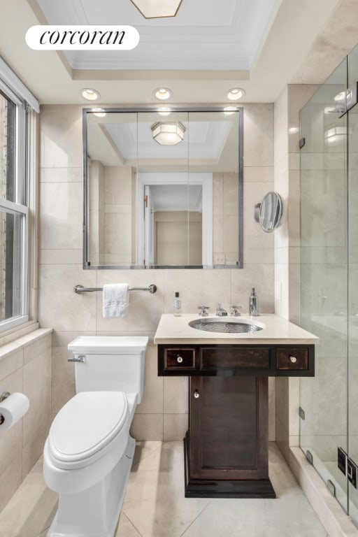 bathroom featuring toilet, crown molding, a raised ceiling, and tile walls