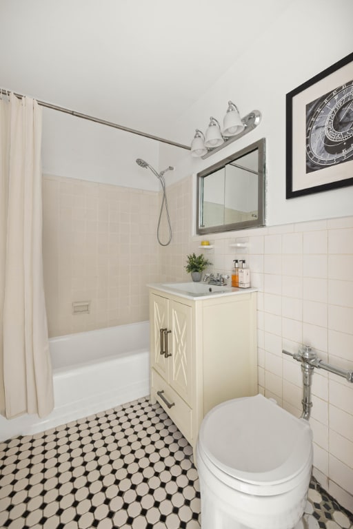 full bath with toilet, vanity, shower / bath combination with curtain, and tile walls