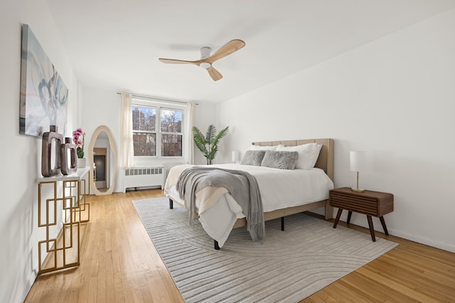 bedroom with radiator, light hardwood / wood-style flooring, and ceiling fan