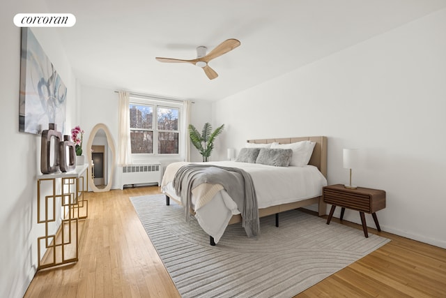 bedroom featuring ceiling fan, visible vents, baseboards, light wood-type flooring, and radiator