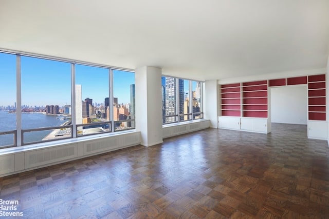 empty room featuring dark parquet flooring and a water view