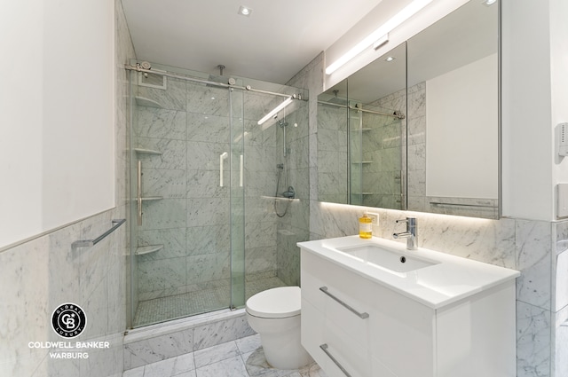 bathroom featuring vanity, a shower with door, tile walls, and toilet