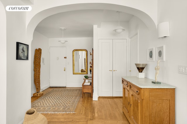 hallway featuring light wood finished floors, visible vents, and baseboards