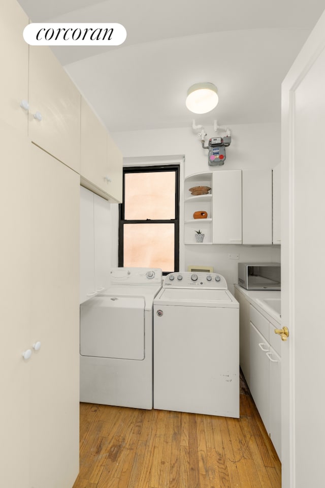 laundry area featuring light wood-type flooring, cabinet space, and separate washer and dryer