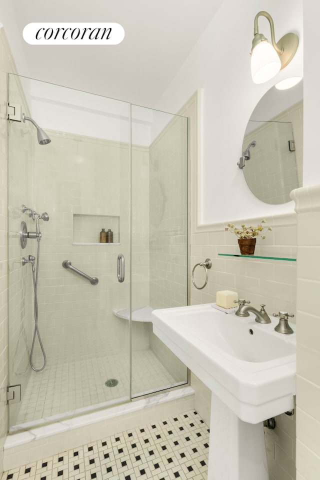 full bath with tile patterned floors, a shower stall, tile walls, and wainscoting