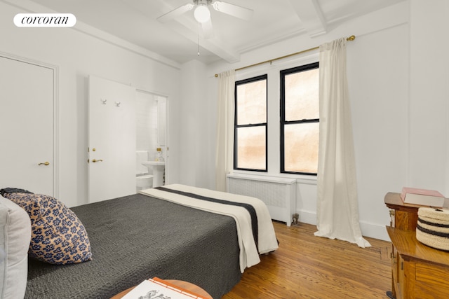 bedroom featuring ensuite bath, ceiling fan, beam ceiling, radiator heating unit, and wood-type flooring