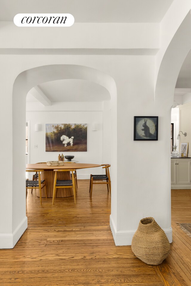 bedroom featuring ensuite bathroom, radiator, hardwood / wood-style floors, ceiling fan, and beam ceiling