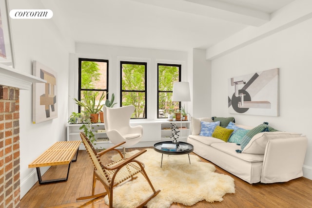 living area with beamed ceiling, wood finished floors, visible vents, and baseboards