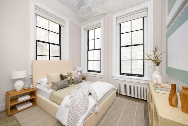 bedroom with radiator heating unit and light hardwood / wood-style floors