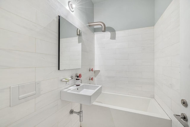 bathroom featuring tiled shower / bath combo, sink, and tile walls