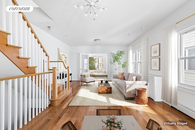 living area featuring visible vents, stairway, light wood-style floors, an inviting chandelier, and baseboards