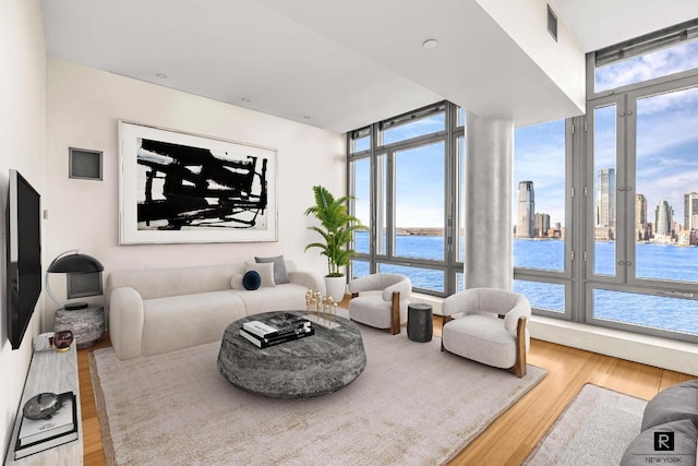 living room with a wealth of natural light, a water view, and light wood-type flooring