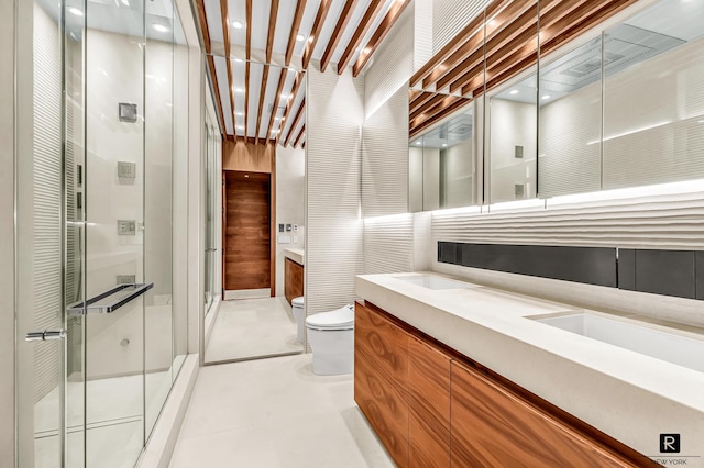 bathroom featuring toilet, a shower stall, and double vanity