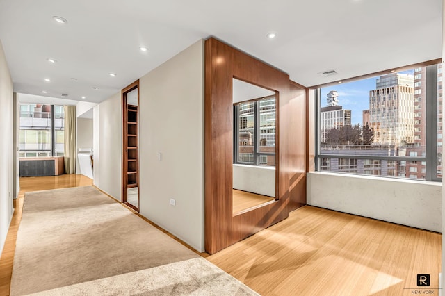 hall featuring wood finished floors, recessed lighting, and a view of city