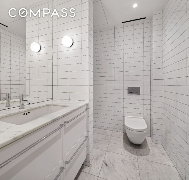 bathroom featuring vanity, tile walls, and toilet