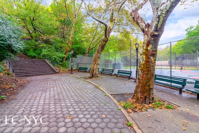 surrounding community featuring a tennis court and fence