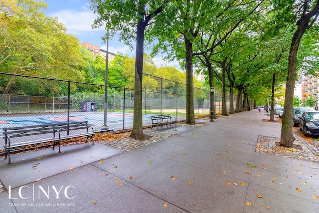 view of home's community featuring a tennis court and fence