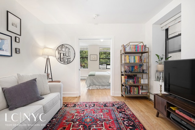 living area featuring baseboards, a baseboard heating unit, and wood finished floors