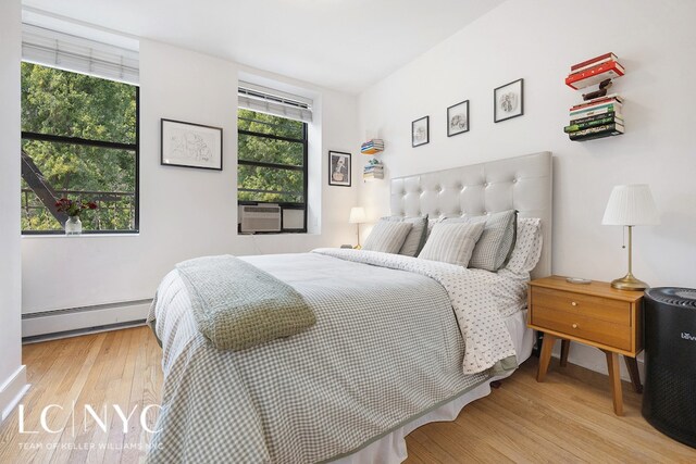 bedroom featuring cooling unit, baseboard heating, and wood finished floors