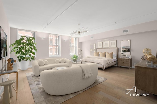 bedroom featuring an inviting chandelier and light wood-type flooring