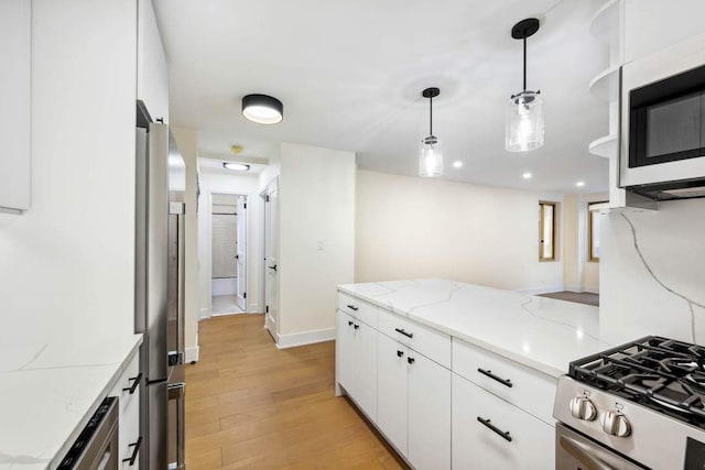 kitchen featuring white cabinetry, appliances with stainless steel finishes, light stone countertops, and hanging light fixtures