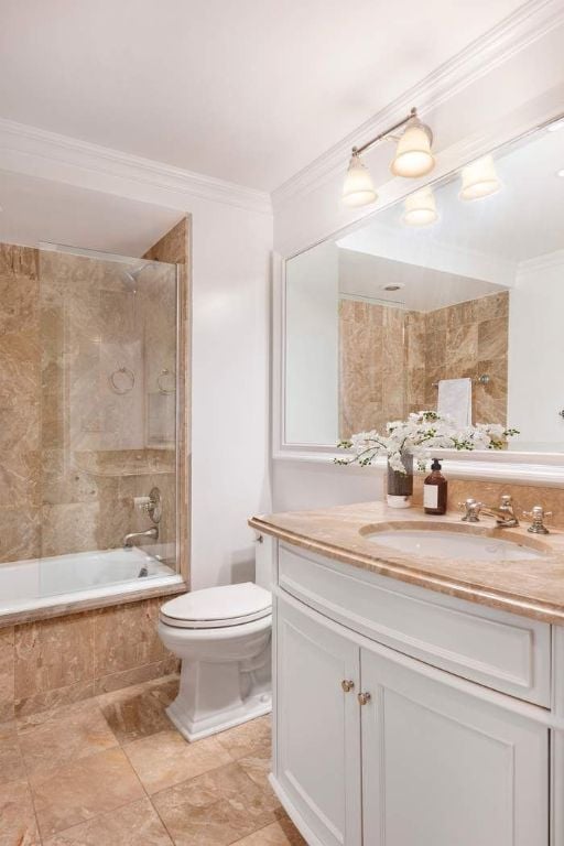 full bathroom featuring crown molding, vanity, toilet, and tiled shower / bath combo