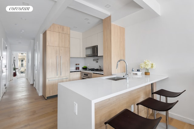 kitchen with a breakfast bar area, visible vents, a sink, modern cabinets, and a peninsula