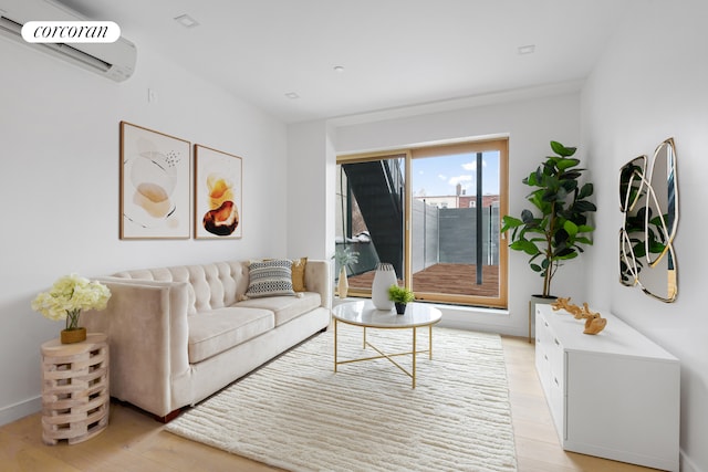 living room with an AC wall unit, baseboards, and light wood finished floors