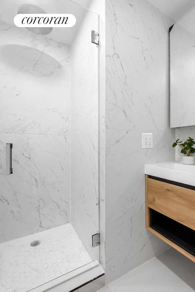 full bath featuring a marble finish shower and vanity