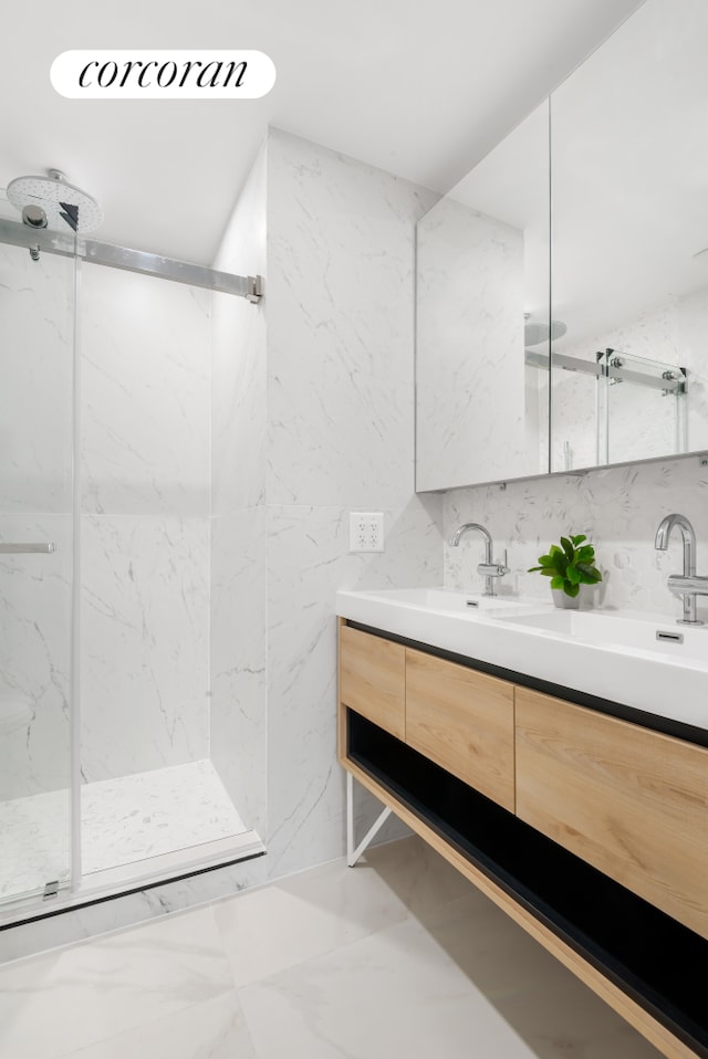 bathroom with double vanity, marble finish floor, a marble finish shower, and a sink