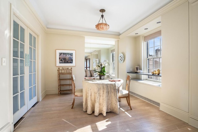 dining area with light hardwood / wood-style flooring, ornamental molding, and french doors